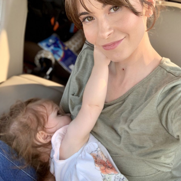 Mom nursing her baby in a Nursing Queen shirt in her car.