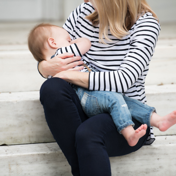 Mom nursing her baby wearing a striped breastfeeding shirt