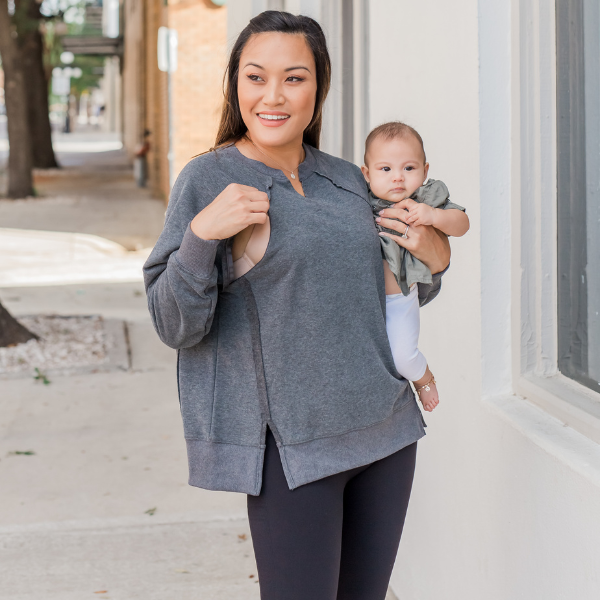 Mom wearing a gray oversized nursing sweatshirt with hidden breastfeeding access