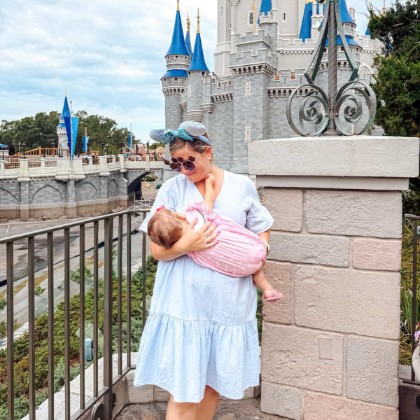 Mother breastfeeding baby in a breathable cotton nursing dress in front of Cinderella Castle at Walt Disney World