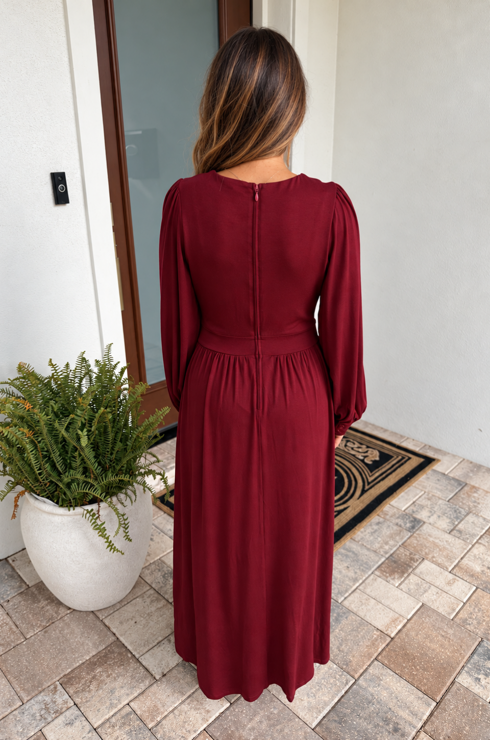 Back view of a mom wearing a nursing and maternity dress in deep spice red