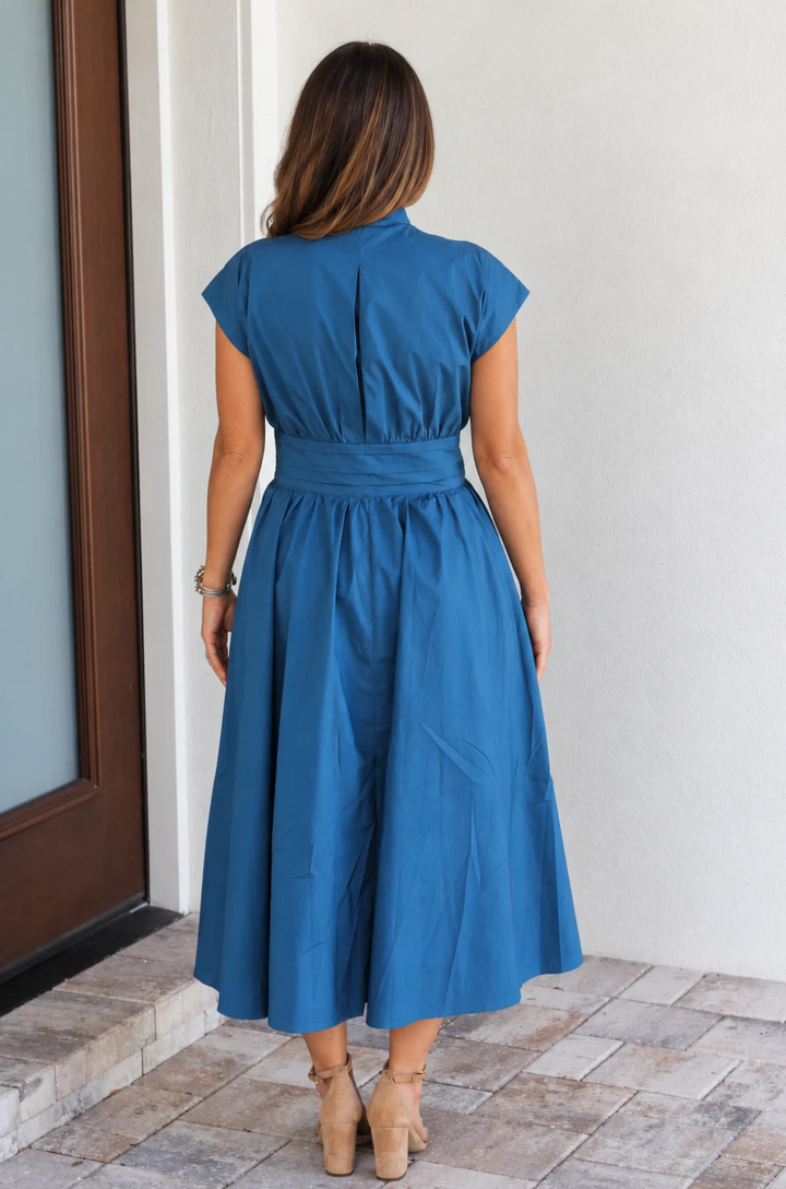 Back view of a mom wearing a cotton breastfeeding dress in a peacock blue color