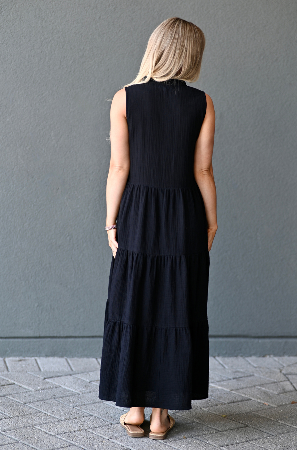 Back view of a woman wearing a black cotton nursing dress with hidden zipper access for breastfeeding. 