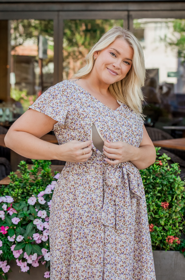 A close-up of the hidden zipper breastfeeding access on the Nursing Queen beige floral belted midi dress highlights the functional design.