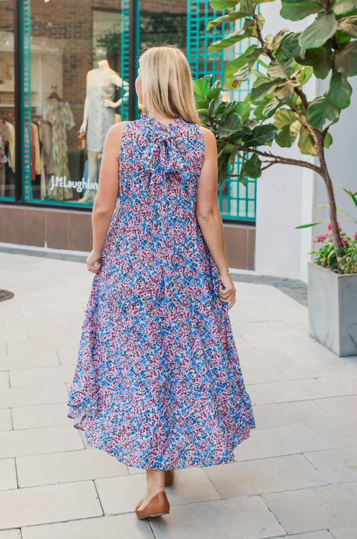 The berry garden tie-back bow breastfeeding dress is shown from the back on a mom, highlighting its feminine floral pattern and relaxed fit.