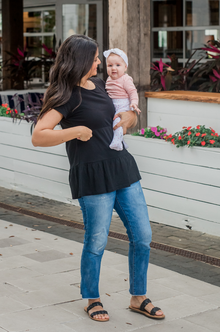 Breastfeeding mom holding her daughter while wearing a navy black nursing top with hidden zipper access for feeding on the go. 