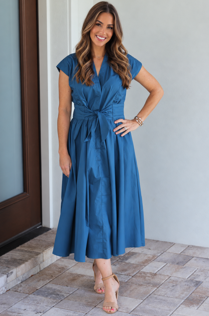 Mom wearing a cotton nursing dress in a peacock color standing on the front porch 
