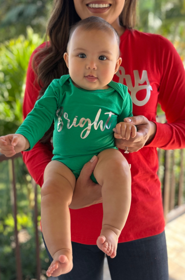 Baby wearing a green onesie that says Bright. 