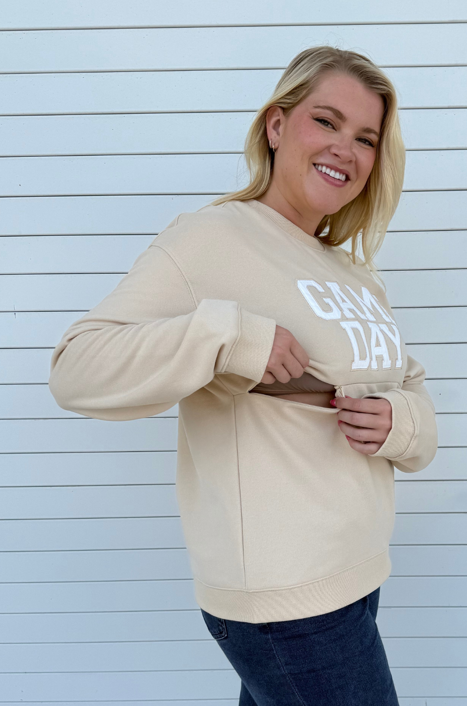 Woman showing nursing access in a game day sweatshirt 