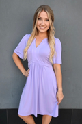 Breastfeeding mom wearing lilac short sleeve nursing dress with hidden zipper access, flattering postpartum fit, and pockets by Nursing Queen