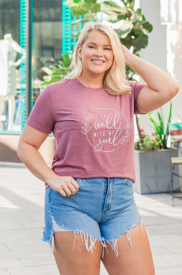 Woman wearing a heather plum breastfeeding T-shirt styled with shorts.