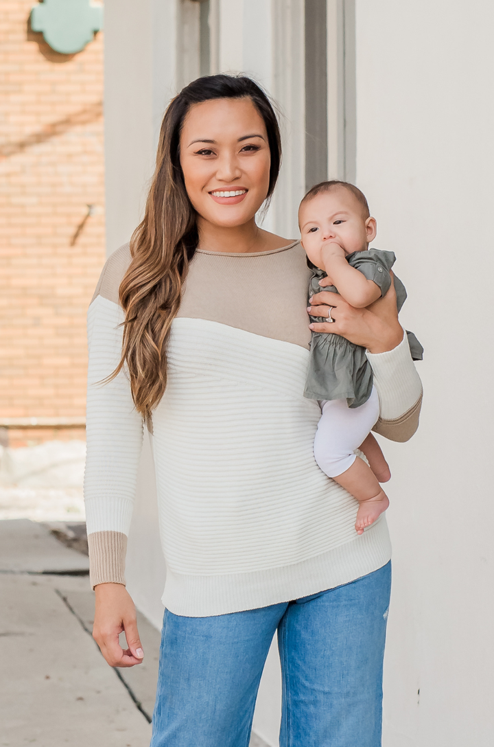 Front view of tan and cream ribbed knit breastfeeding sweater featuring concealed zipper nursing access.