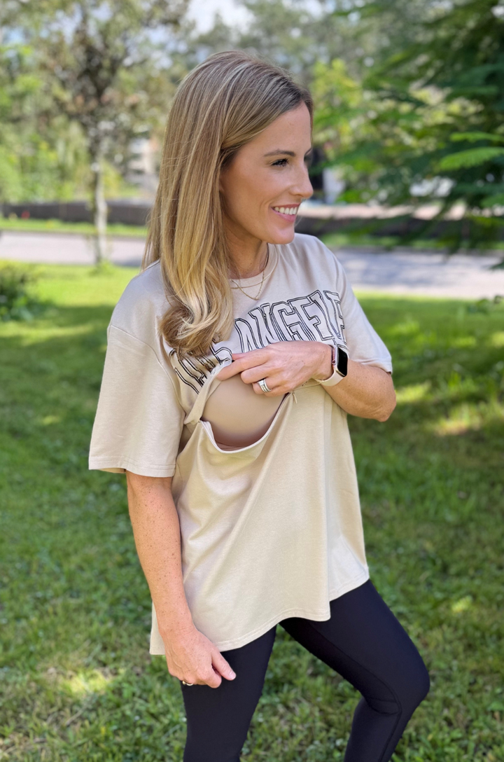 A mom opens the hidden zipper breastfeeding access on the Los Angeles California tan graphic t-shirt to nurse in public.