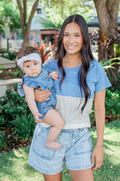 Mom holding her baby wearing a blue and striped nursing tee with hidden breastfeeding access