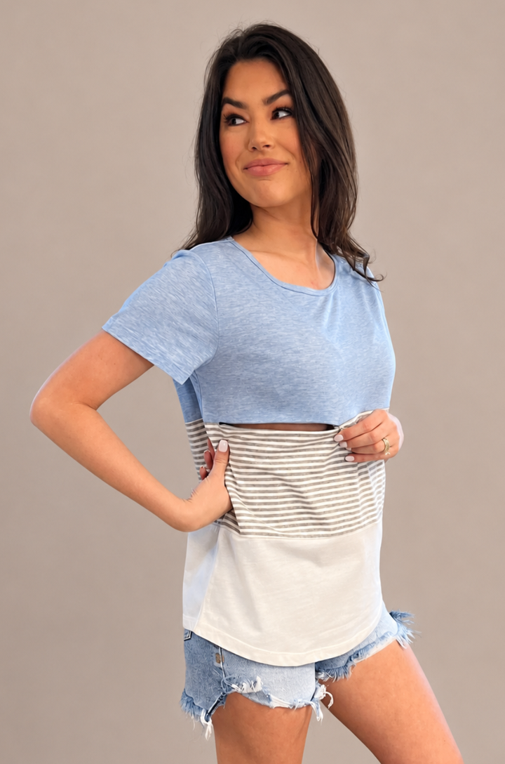 A close-up shows a mom opening the hidden zipper breastfeeding access on the blue 3-block colorblock t-shirt for discreet nursing.