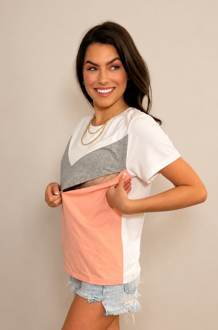 A mom opens the hidden zipper breastfeeding access on the Chevron colorblock hot peach t-shirt to nurse comfortably.