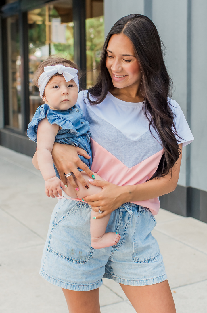 A mom wears the Chevron colorblock hot peach breastfeeding t-shirt paired with shorts for a comfortable, everyday outfit.