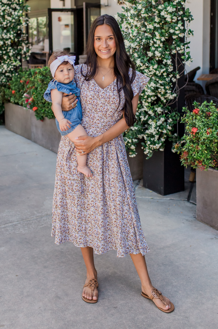 Mom wearing a floral beige midi nursing dress with hidden breastfeeding access