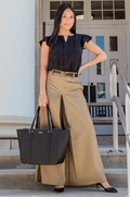 Woman in black breastfeeding top and beige wide-leg pants holding a black handbag on steps.