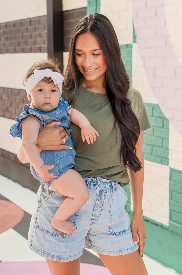 Mom holding her baby wearing an olive green nursing top with hidden breastfeeding access