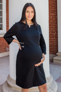 Woman in a black maternity and nursing dress standing in front of a building with columns.