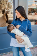 Woman nursing her baby while wearing a breastfeeding sweatshirt in front of a store window