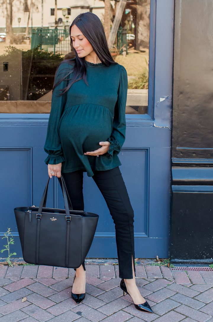 Mom wearing a dark green maternity and nursing sweater with hidden breastfeeding access. 