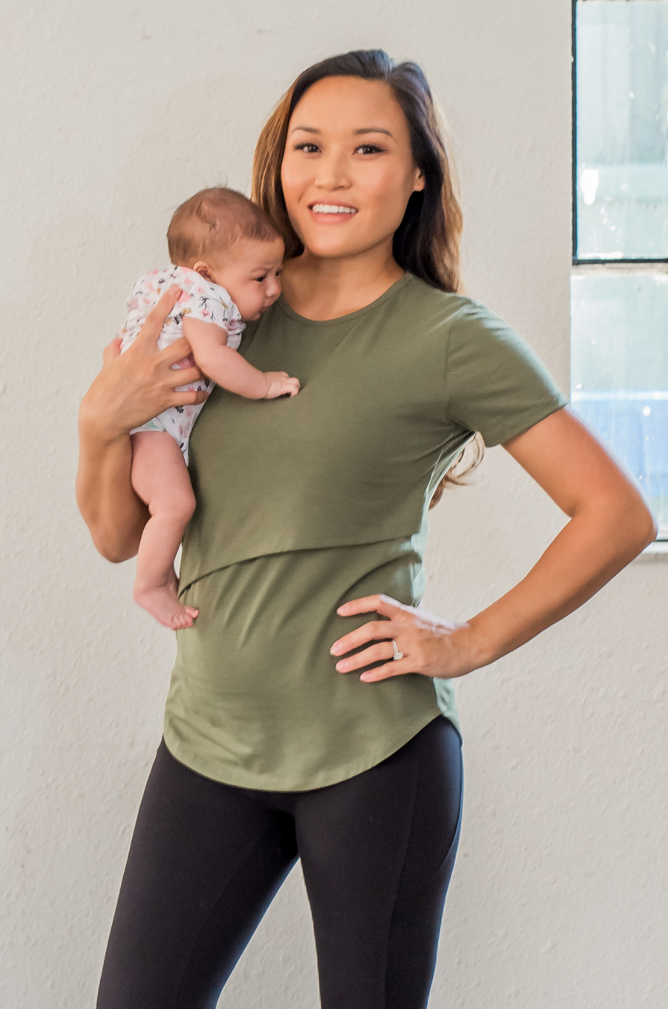 Woman holding a baby and wearing an olive green nursing shirt with a pocket.