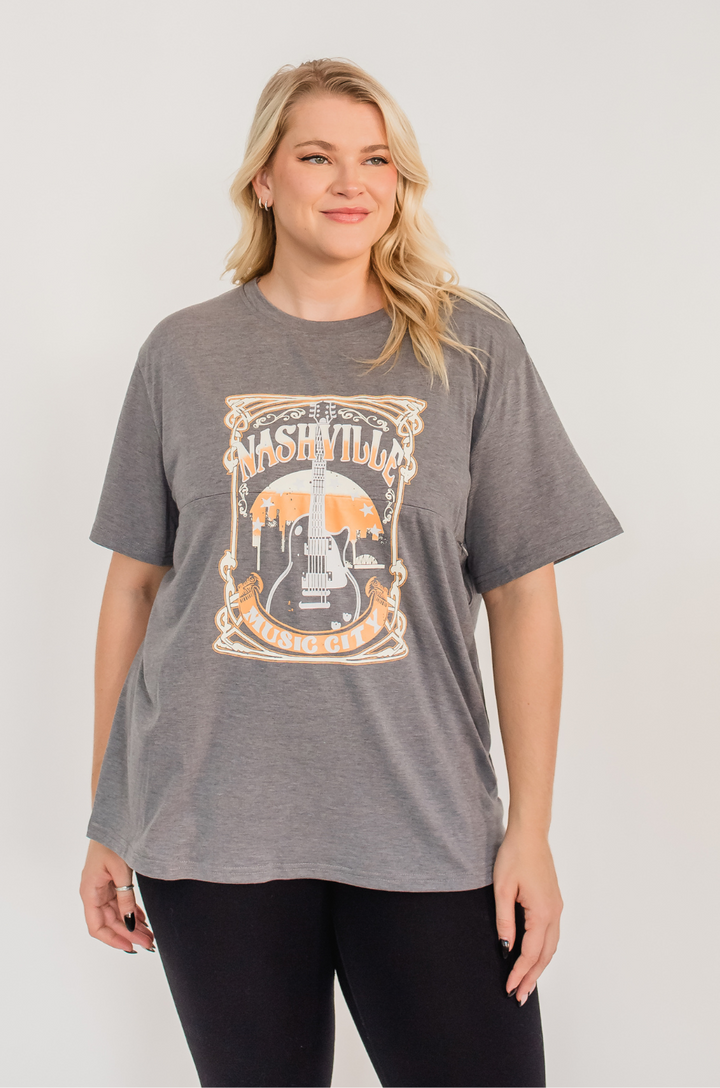 A mom wears the Nashville nursing graphic gray t-shirt paired with leggings for a comfortable, everyday outfit.