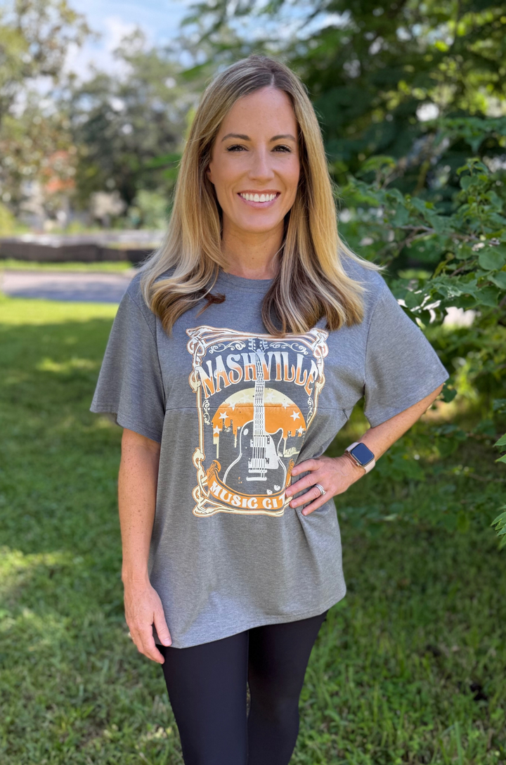 A mom stands casually in leggings while wearing the Nashville nursing graphic gray t-shirt, showing an effortless everyday look.