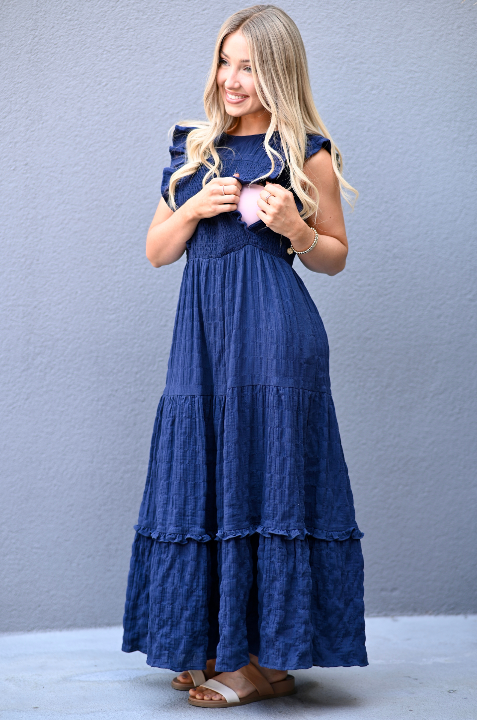 Woman wearing a blue cotton nursing dress showing how the hidden nursing access works