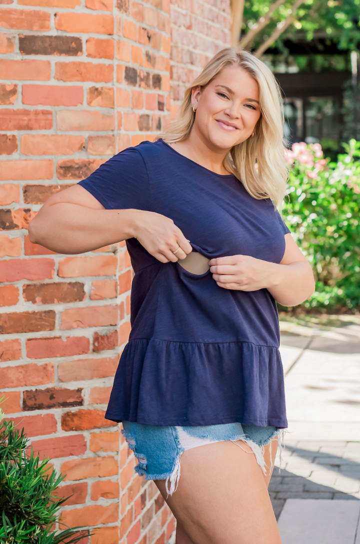 Casual outfit showing a mom wearing shorts and a cotton breastfeeding top with the zipper partially open for nursing. 