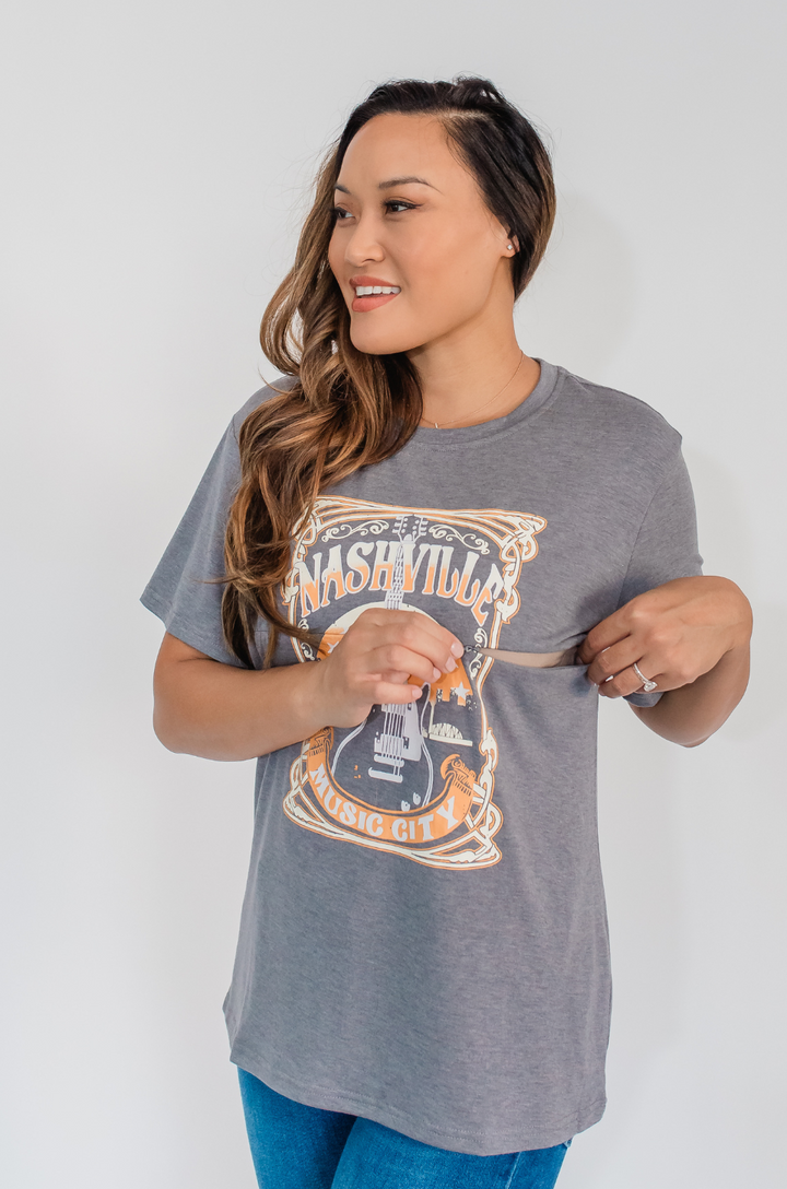 A close-up shows the hidden zipper breastfeeding access on the Nashville nursing graphic gray t-shirt for discreet feeding.