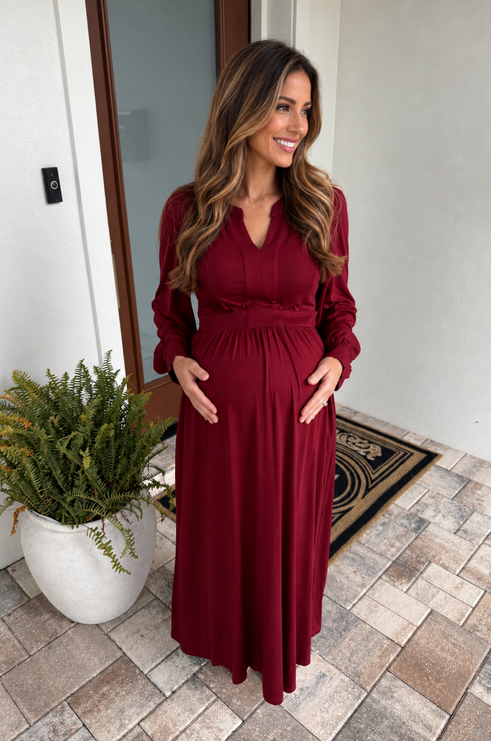 A pregnant woman wearing a deep red maternity and nursing dress for the fall and winter