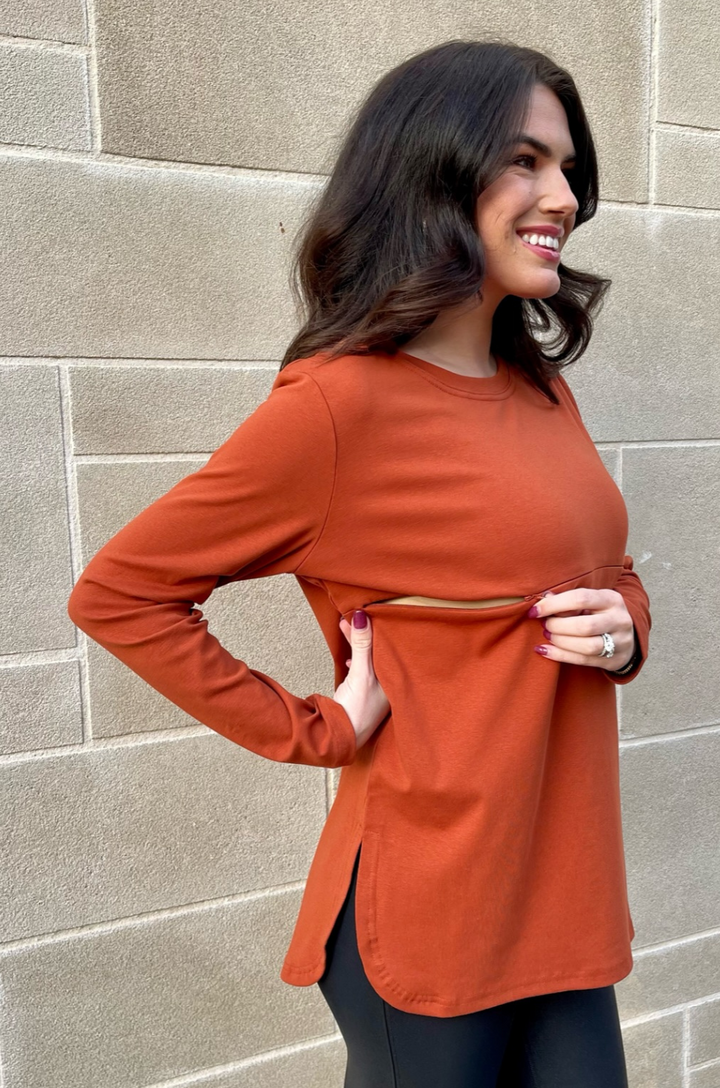 Close-up of concealed zipper breastfeeding access on rust long sleeve nursing tunic, partially opened