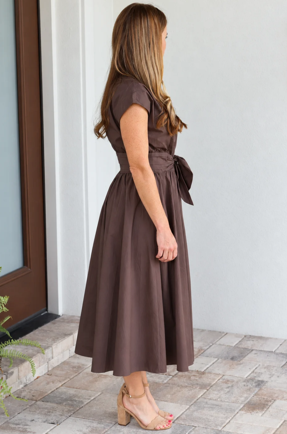 Side view of a mom wearing a brown cotton nursing dress with hidden access for pumping and nursing, and pockets. 