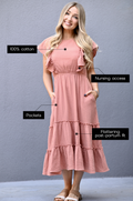 Woman wearing a terracotta gauze midi nursing dress made from 100% cotton with hidden zipper nursing access, pockets, and flattering postpartum fit.