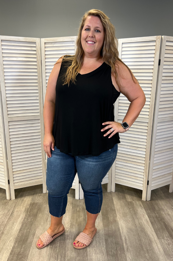 Front view of plus-size breastfeeding mom wearing the black swing nursing tank top styled with jeans, showing flowy silhouette and side opening nursing access