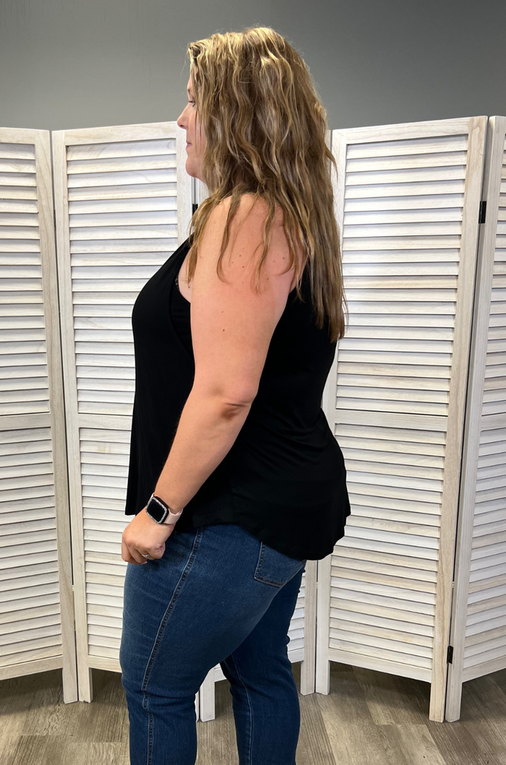 Side view of plus-size breastfeeding mom wearing the black swing nursing tank top styled with jeans.