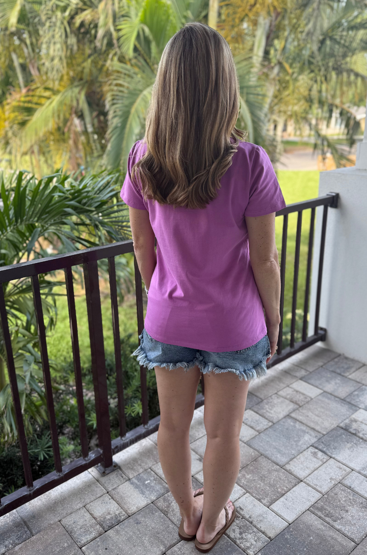 Back view of a mom wearing a purple breastfeeding shirt, showing relaxed fit and short sleeves with sandals. 