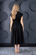 A woman viewed from behind wearing a black midi cotton nursing dress with cap sleeves and a defined waist