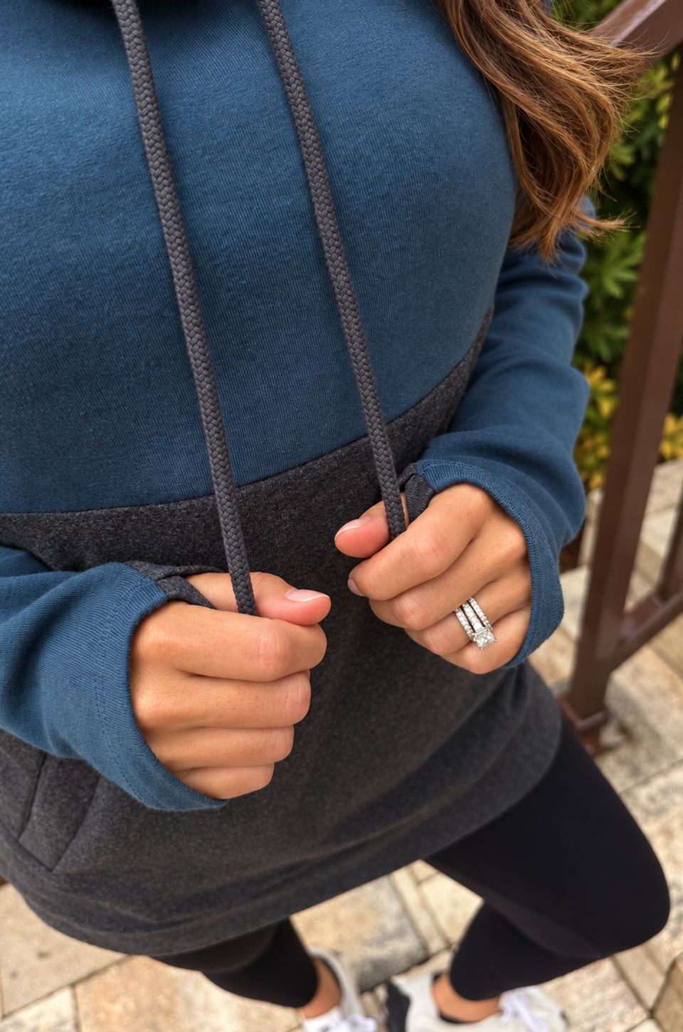 A close up view of a woman holding the hoodie strings for a breastfeeding nursing sweatshirt 