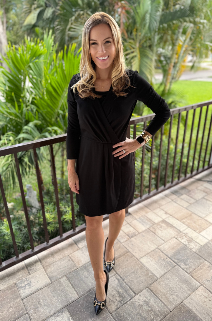 Breastfeeding mom wearing black ponte knit faux wrap nursing dress