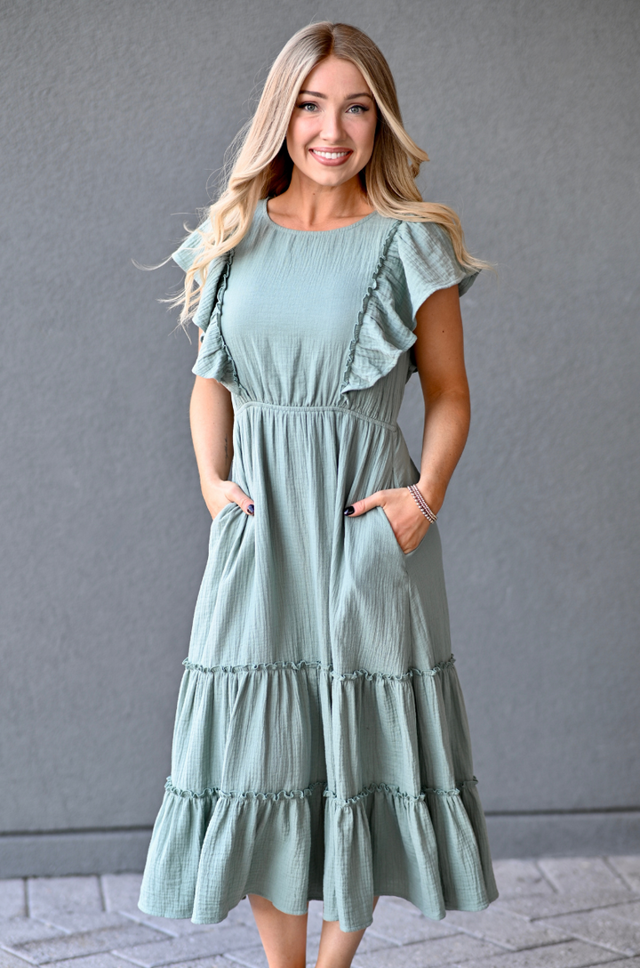 Woman wearing a seafoam green gauze midi nursing dress with hidden zipper breastfeeding access and pockets by Nursing Queen.