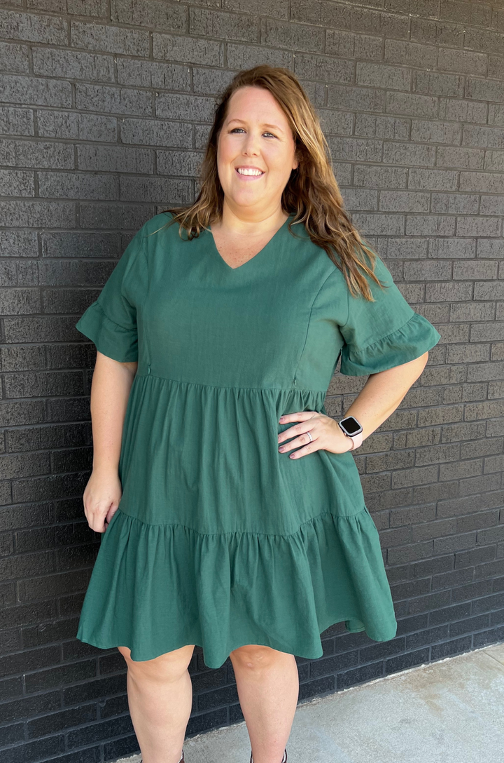 Plus-size model wearing the green bell sleeve nursing dress with pockets with a relaxed, flattering fit for postpartum bodies.