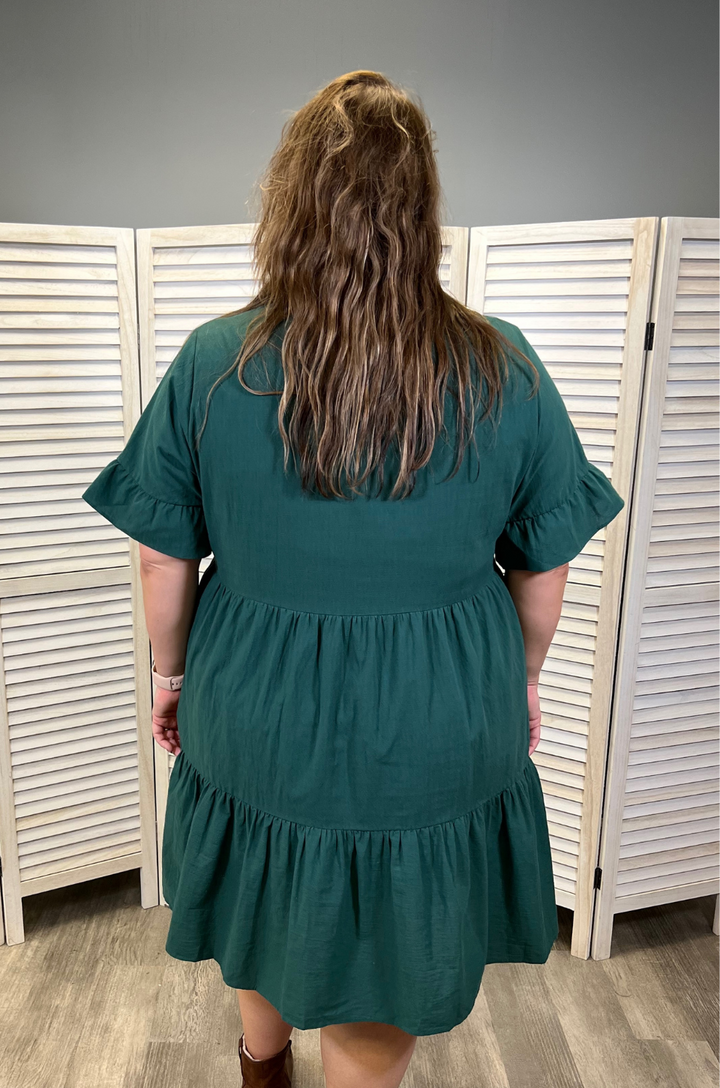 A back view highlights the flowing shape and comfortable fit of the green bell sleeve breastfeeding dress with pockets.