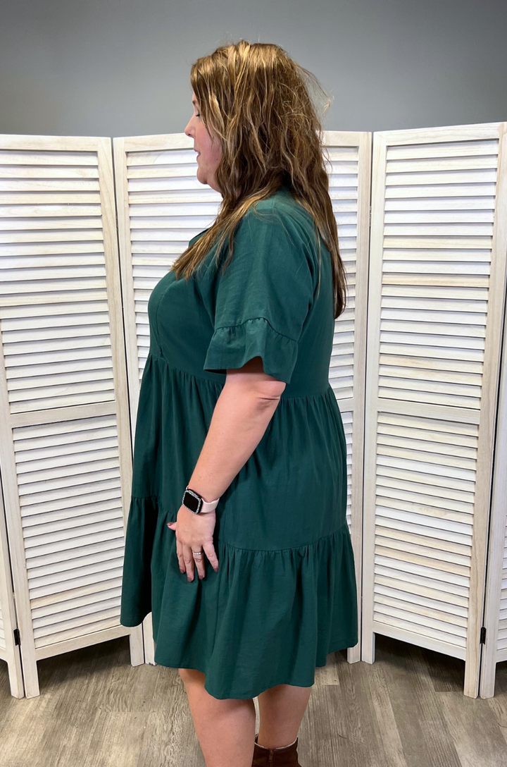 Side view of the green bell sleeve nursing dress with pockets displays its flowing silhouette and functional design.