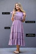 Woman wearing a lavender gauze midi nursing dress made from 100% cotton with hidden zipper nursing access, pockets, and flattering postpartum fit.