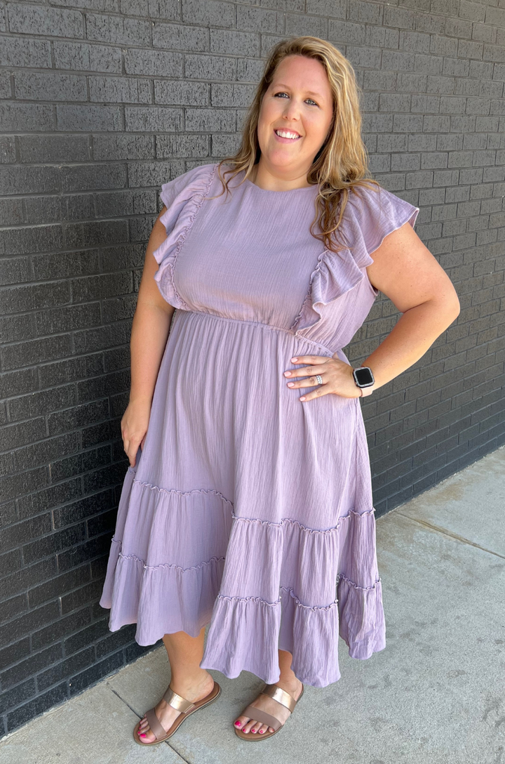A front view shows a plus-size mom wearing the lavender gauze ruffle midi breastfeeding dress made from soft cotton, highlighting a flattering and comfortable fit.