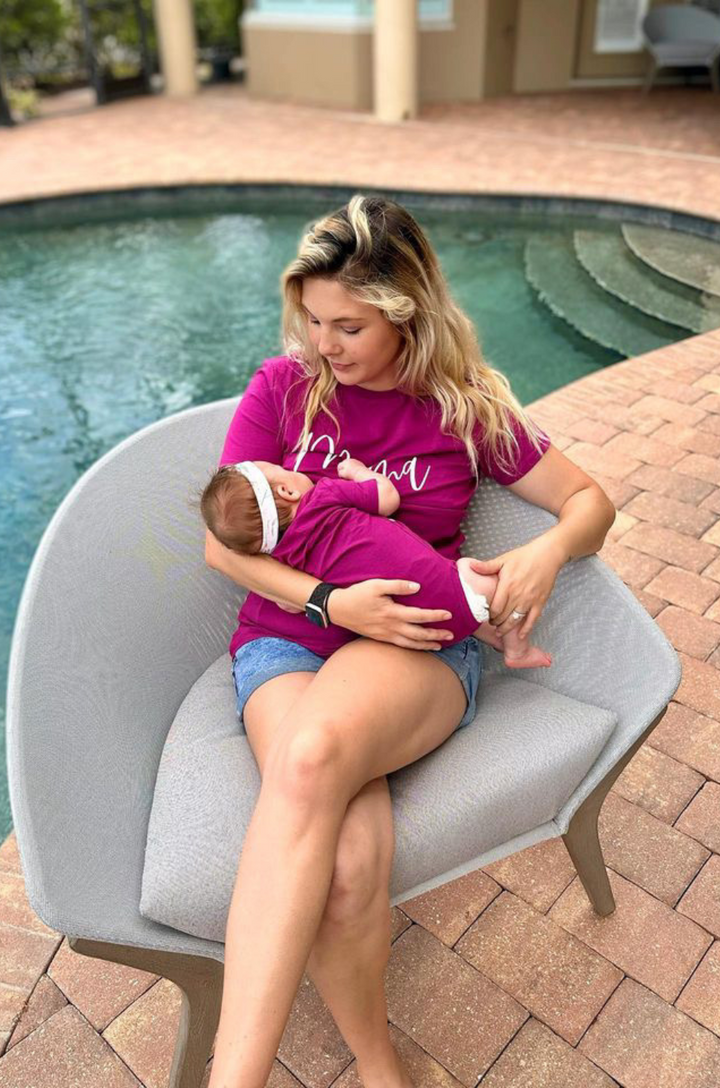 Mom nursing her daughter in a berry shirt with the text "mama" on the front. 